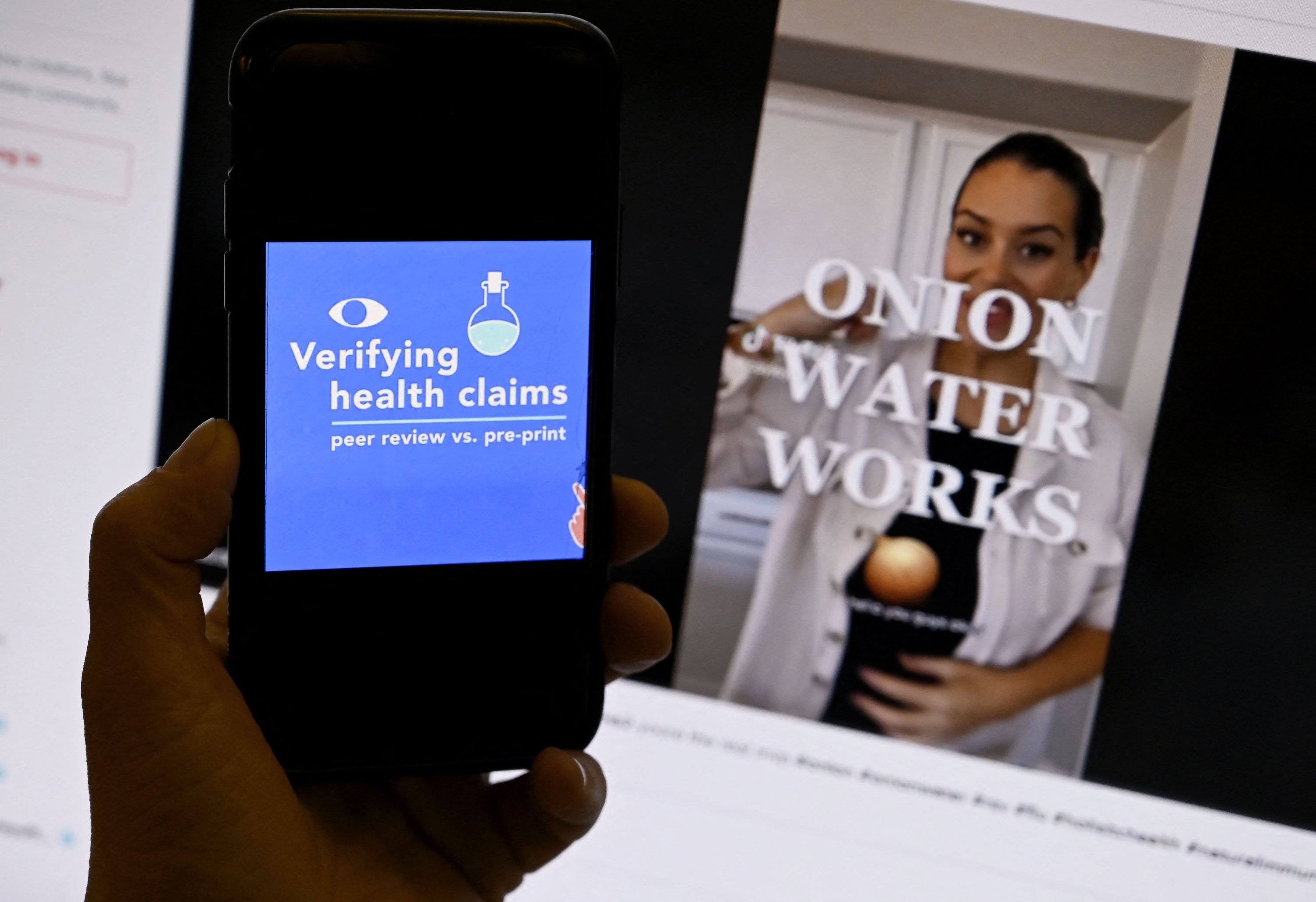 Halaman verifikasi klaim kesehatan dari AFP Fact Check ditampilkan di ponsel dengan video TikTok Air Bawang yang ditampilkan di latar belakang di Washington DC, AS, 20 Desember 2022. (Foto AFP)