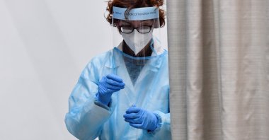 A health worker wearing personal protective equipment places a COVID-19 test swab in a vial, at the Malpensa Airport in Milan, Italy, Dec. 29, 2022. (Reuters Photo)