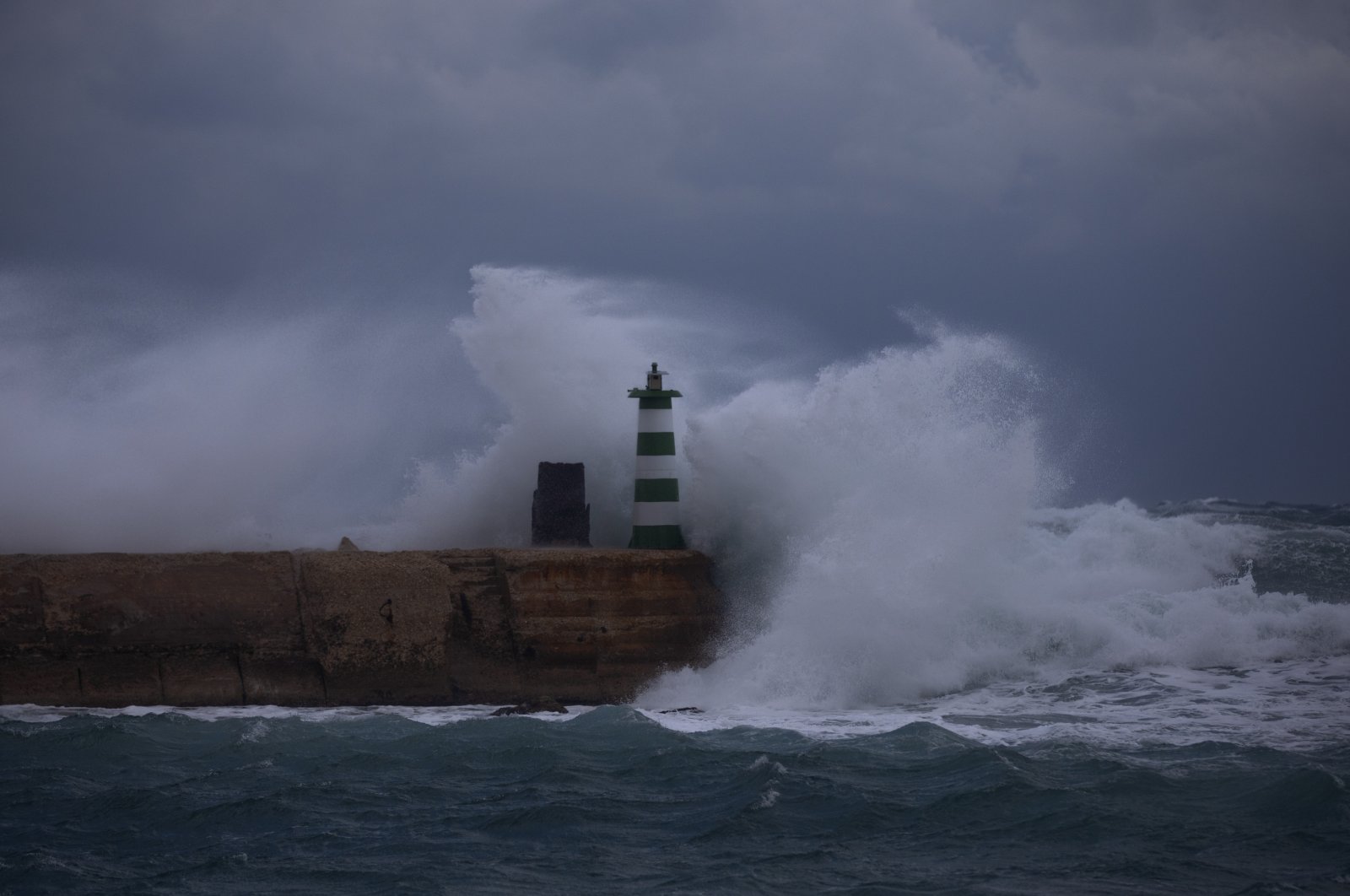 Waves break on a pier near the lighthouse during stormy weather at the port of Jaffa, Israel, Dec. 20, 2021. (AP Photo)