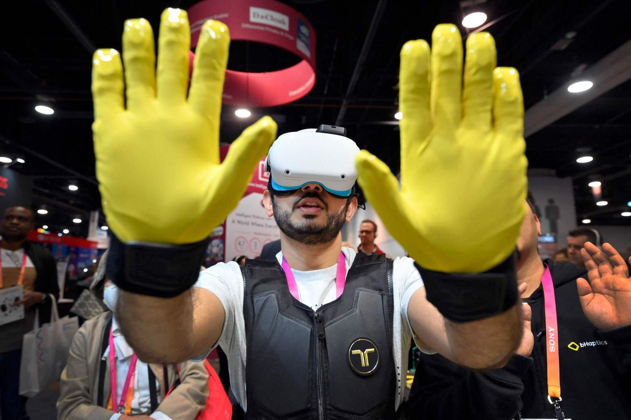 Seorang peserta menggunakan sarung tangan taktil dan rompi saat dia menggunakan demonstrasi VR di stan bHaptics selama CES 2023 di Las Vegas Convention Center, di Las Vegas, AS, 6 Januari 2023. (Foto AFP)