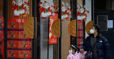 A man and a child walk past a bread shop decorated with rabbit patterns on doors, Beijing, Jan. 10, 2023. (AFP Photo)