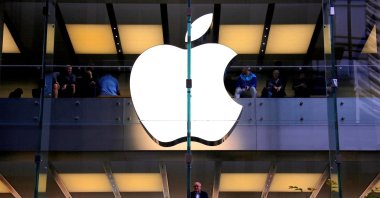A customer stands underneath an illuminated Apple logo as he looks out the window of the Apple store located in central Sydney, Australia, May 28, 2018. (Reuters Photo)