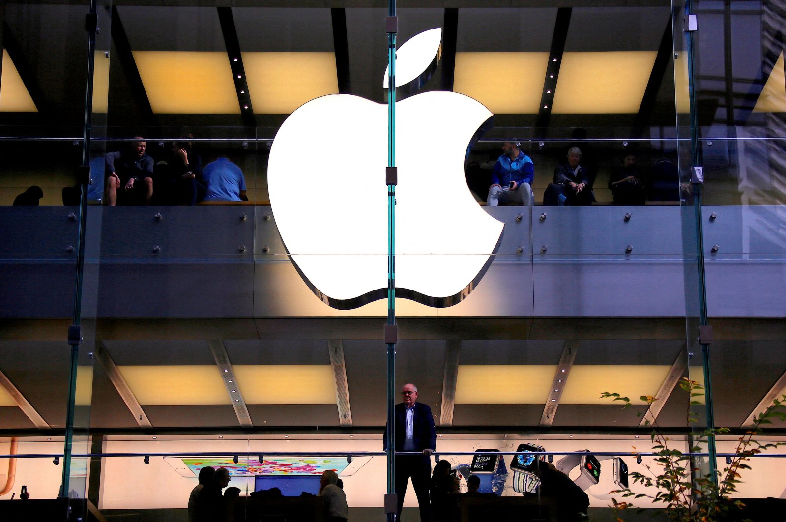 A customer stands underneath an illuminated Apple logo as he looks out the window of the Apple store located in central Sydney, Australia, May 28, 2018. (Reuters Photo)