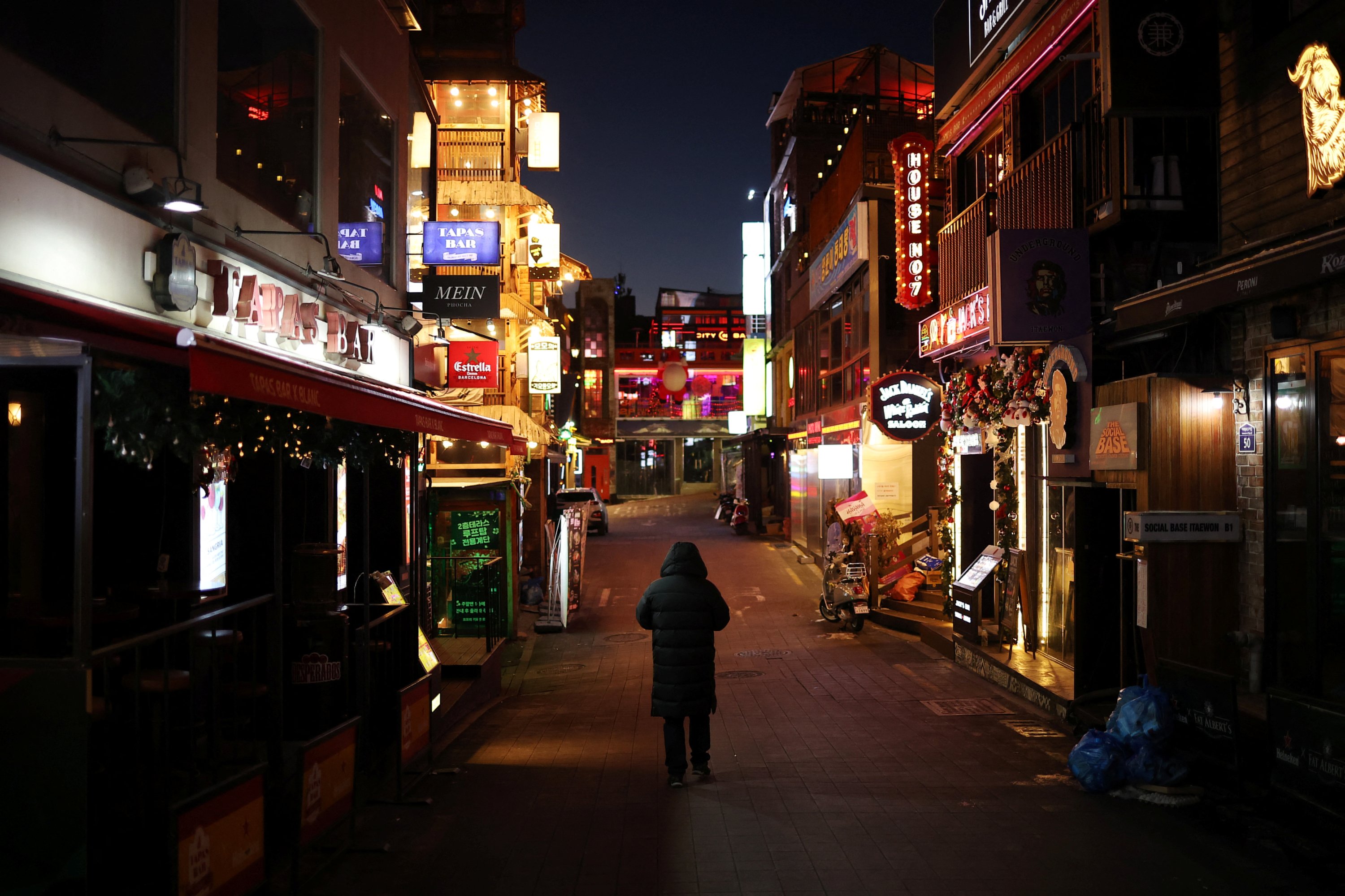 Seorang pria berjalan di jalan kosong Itaewon di dekat tempat perayaan Halloween mematikan yang menewaskan lebih dari 150 orang pada bulan Oktober terjadi, di Seoul, Korea Selatan, 18 Desember 2022. REUTERS/Kim Hong-Ji