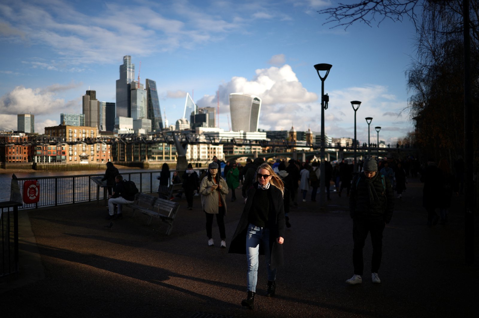 People walk along the bank of the River Thames, with the City of London financial district in the background, in London, Britain, Jan. 2, 2023. (Reuters Photo)