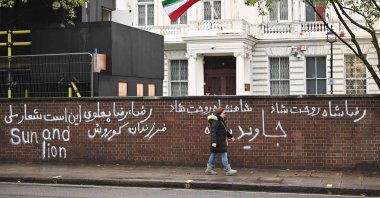 Pedestrians walk past graffiti daubed on a wall outside the Iranian Embassy in London on Jan. 14, 2023. (AFP Photo)