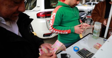 A street money exchanger counts banknotes at the al-Kifah stock market in Baghdad, Iraq, Dec. 27, 2022. (AFP Photo)