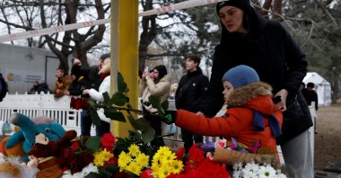 A woman and a child leave tributes near the site where an apartment block was heavily damaged by a Russian missile strike, Dnipro, Ukraine, Jan. 16, 2023. (Reuters Photo)