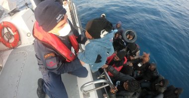 A Turkish guard pulls a baby to safety on the coast guard's boat as the team rescues some 99 asylum-seekers pushed back into Türkiye's territorial waters by Greek authorities off the coast of Izmir province, Jan. 17, 2023. (IHA Photo)