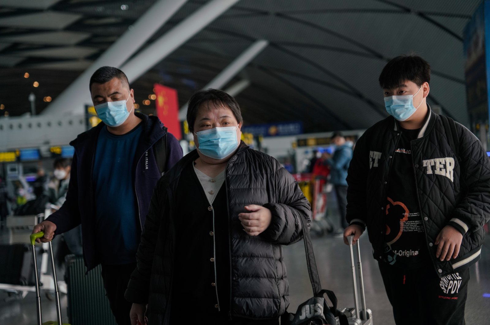 Passengers wearing face masks walk with their luggage at Nanning Wuxu International Airport in Nanning, China, Jan. 18, 2023. (EPA Photo)