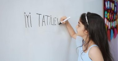 A student writing "İyi tatiller" ("Happy Holidays") on a whiteboard is pictured in Erzincan, Türkiye, Jan. 19, 2023. (IHA Photo)