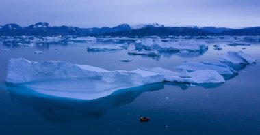 A boat navigates at night next to large icebergs near the town of Kulusuk, in eastern Greenland, Aug. 15, 2019. (AP Photo)