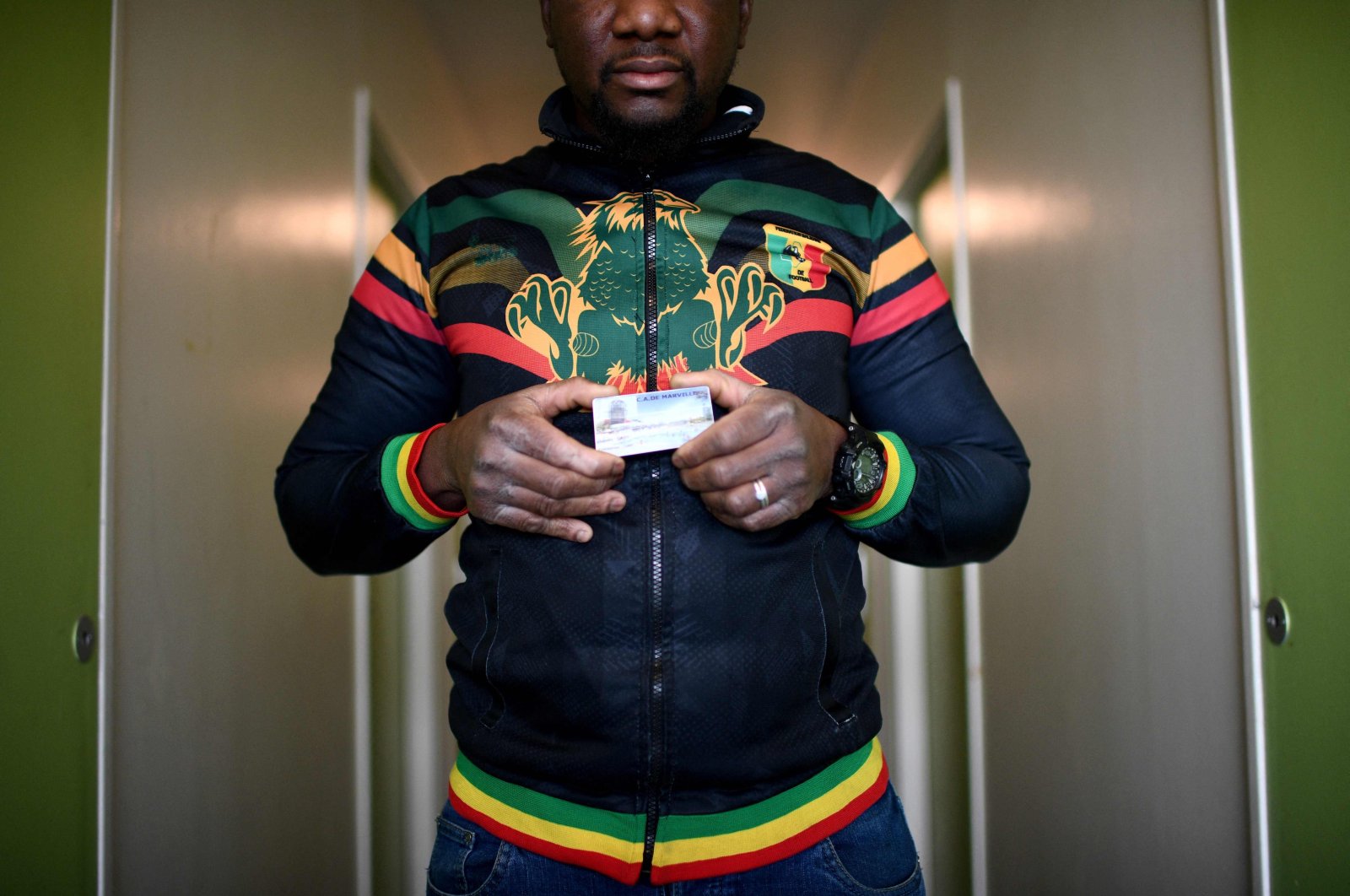 An undocumented worker from Mali holds his access card to the construction site where he used to work illegally, the Marville Aquatics Centre in nearby La Courneuve, which will serve as a training base for the Paris 2024 Olympic Games, Aubervilliers, northern Paris, France, Dec. 15, 2022. (AFP Photo)