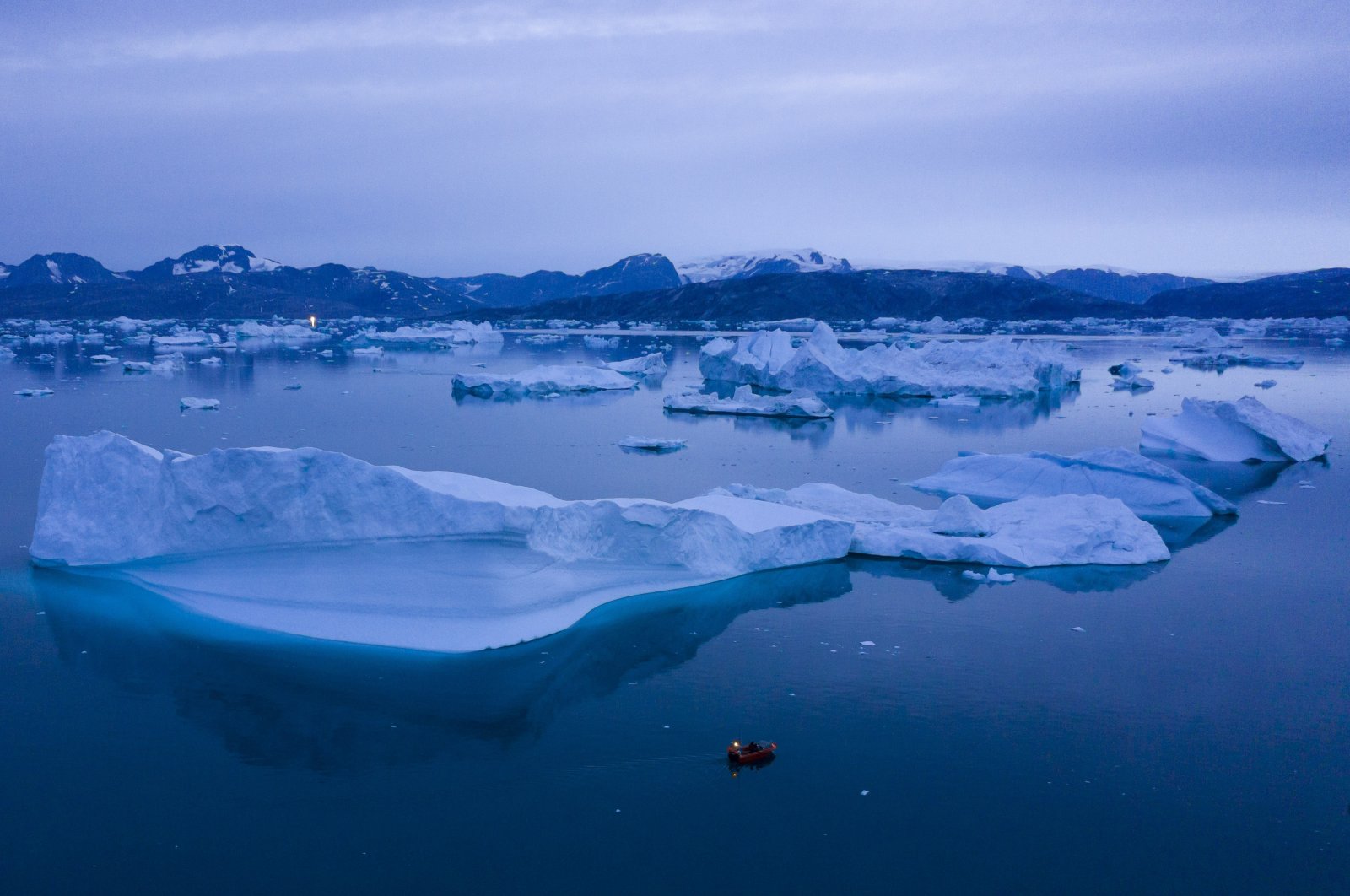 A boat navigates at night next to large icebergs near the town of Kulusuk, in eastern Greenland, Aug. 15, 2019. (AP Photo)