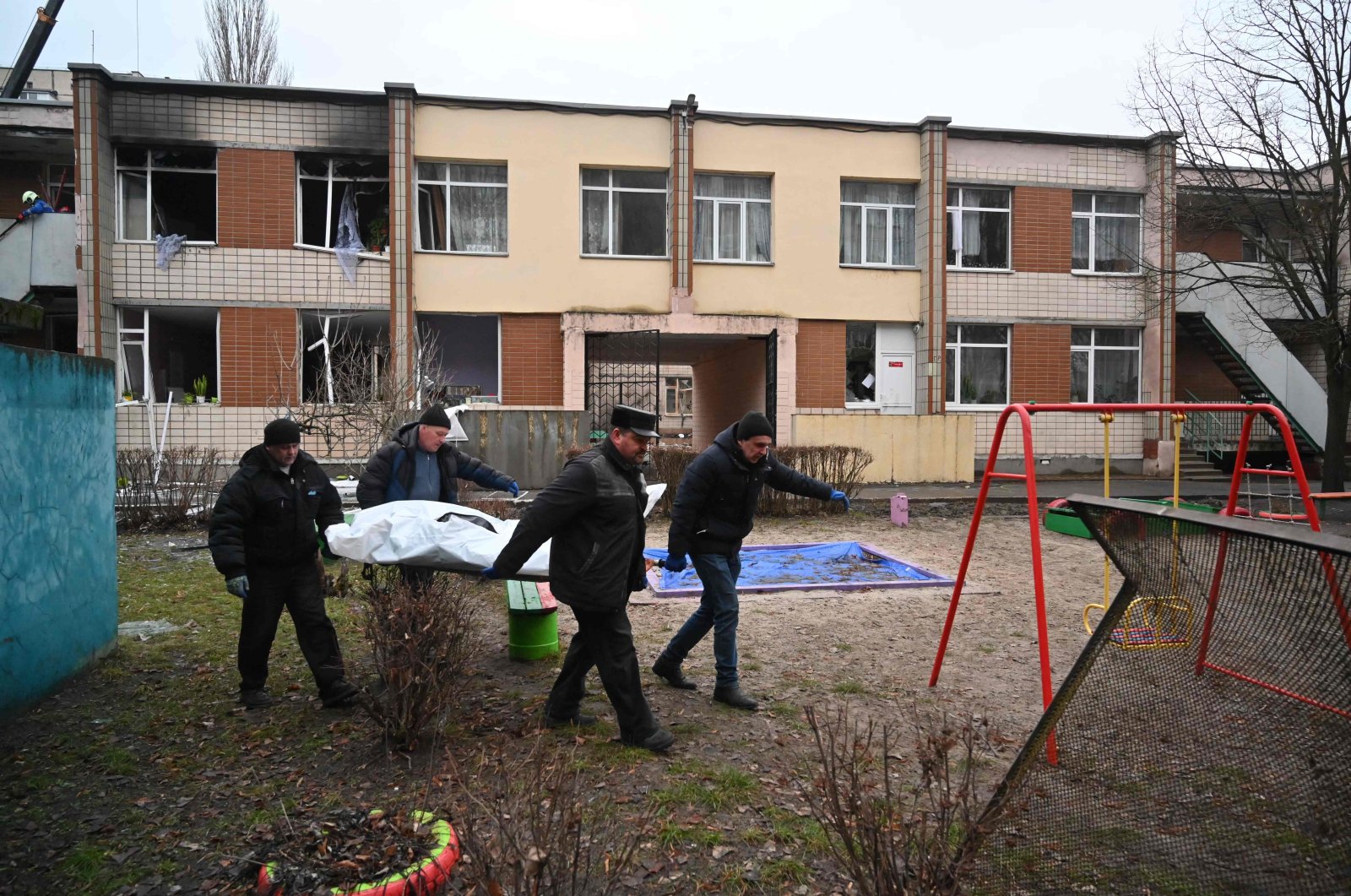 Four men carry a bag with a body at the site where a helicopter crashed near a kindergarten in Brovary, outside the capital Kyiv, Ukraine, Jan. 18, 2023. (AFP File Photo)