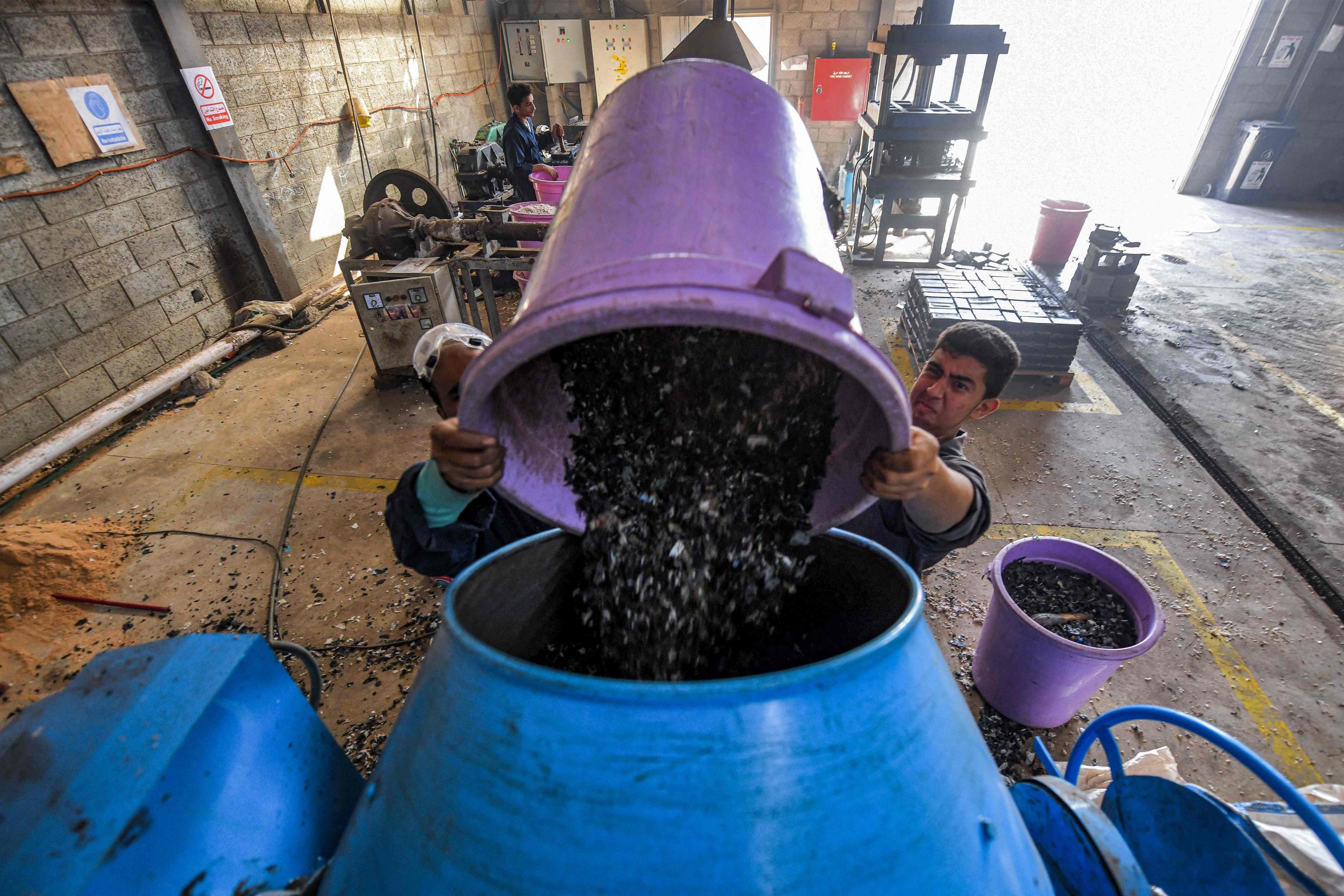 Pekerja membuang sampah plastik ke dalam mixer sebelum didaur ulang menjadi ubin interlocking ramah lingkungan yang digunakan di trotoar luar ruangan di bengkel perusahaan rintisan 