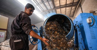 A worker dumps plastic waste out of a mixer before it is to be recycled into eco-friendly interlocking tiles used in outdoor walkways at a workshop of the startup company "TileGreen," Cairo, Egypt, Dec. 18, 2022. (AFP Photo)