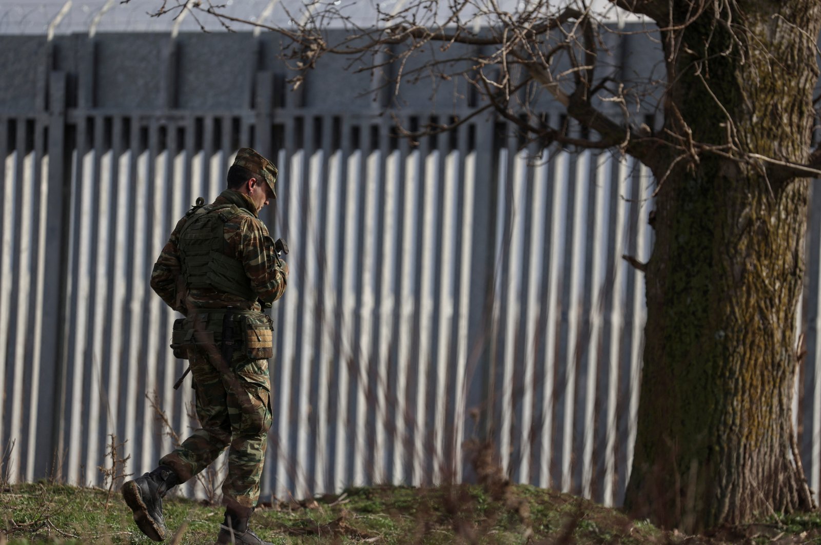 A Greek Army officer walks next to a border fence, built to prevent migrant crossings, during a press tour at the Greek-Turkish border, near the village of Poros, Evros region, Greece, Jan. 21, 2023. (REUTERS Photo)