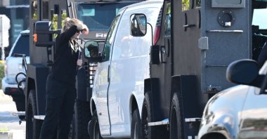 A law enforcement official looks into a van containing what is believed to be a dead body, as seen in the rearview mirror, in Torrance, California, U.S., Jan. 22, 2023. (AFP Photo)