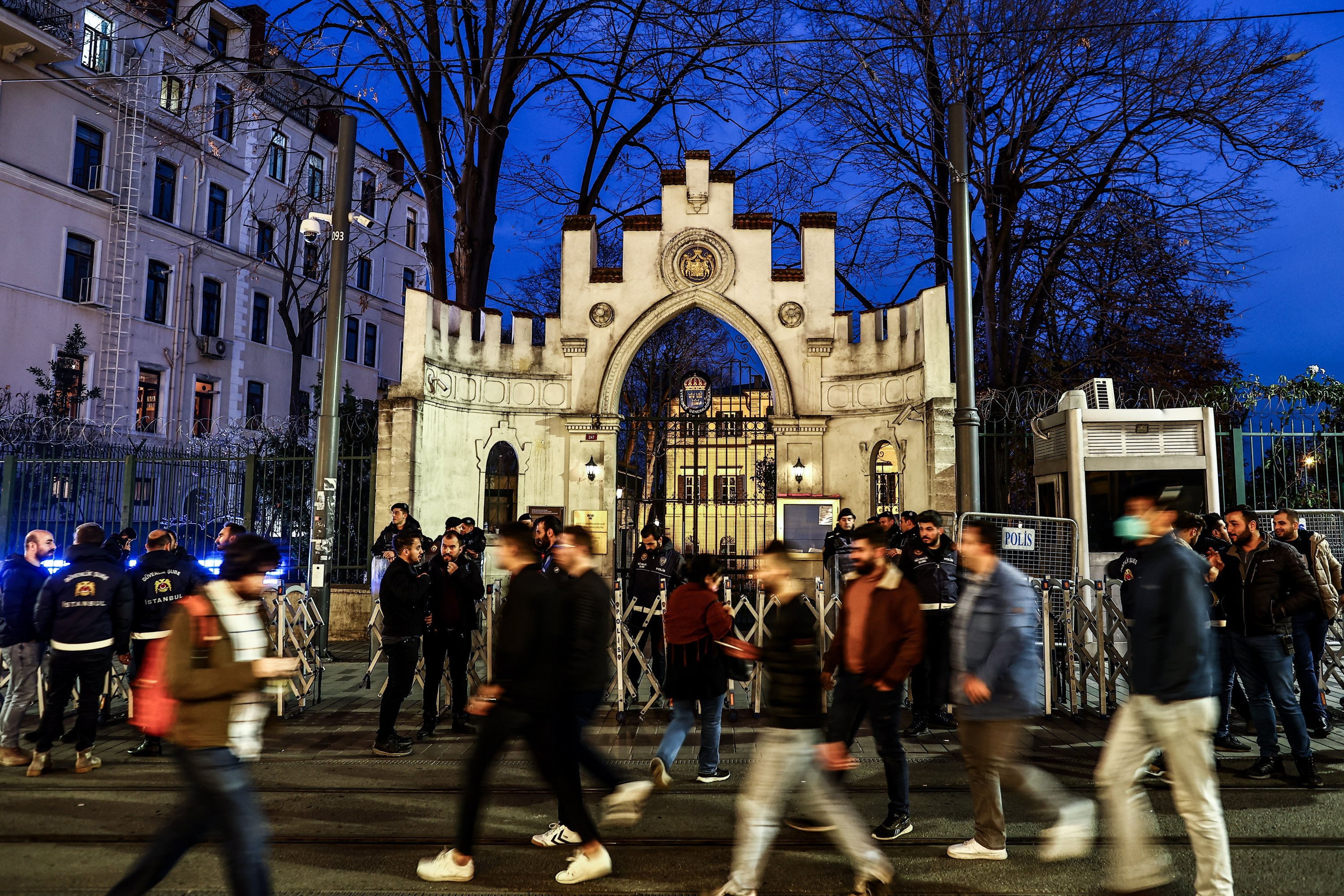 Orang-orang berjalan melewati petugas polisi anti huru hara Turki yang berjaga selama protes di depan Konsulat Jenderal Swedia, di Istanbul, Türkiye, 22 Januari 2023. (Foto EPA)