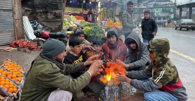 Vendors warm themselves as they light a bonfire at a market during a nationwide power outage, Muzaffarabad, Pakistan, Jan. 23, 2023. (AFP Photo)