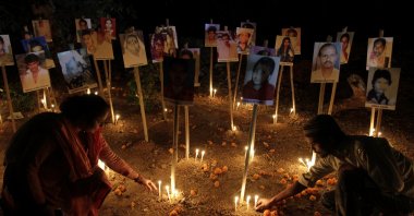 Indians participate in a candlelight vigil to mark the 10th anniversary of the Gujarat riots as photographs of riot victims stand in the background, Ahmadabad, India, Feb. 24, 2012. (AP Photo)