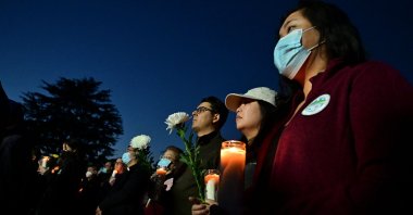 People hold candles as they pay tribute to the victims of the mass shooting at a candlelight vigil in front of City Hall in Monterey Park, California, Jan. 24, 2023. (AFP Photo)
