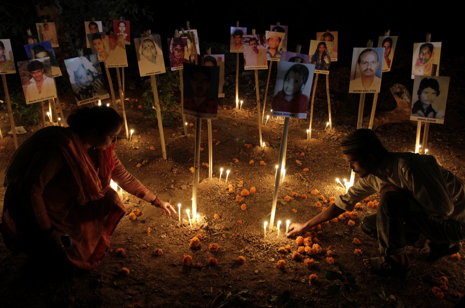 Indians participate in a candlelight vigil to mark the 10th anniversary of the Gujarat riots as photographs of riot victims stand in the background, Ahmadabad, India, Feb. 24, 2012. (AP Photo)