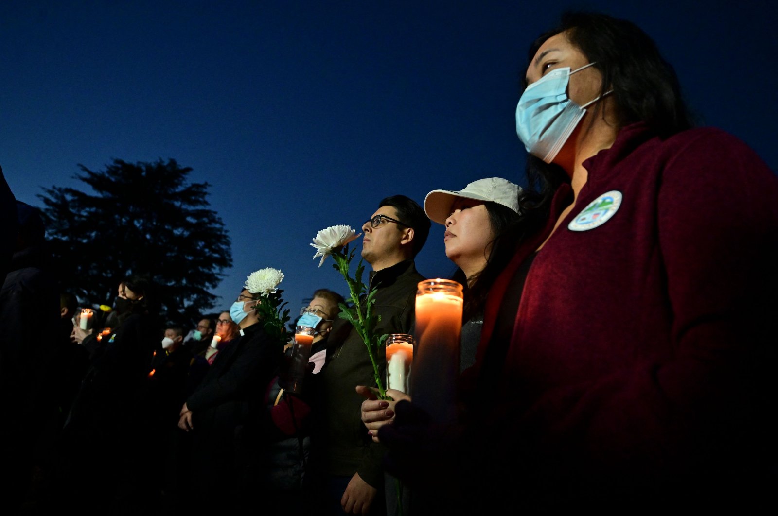People hold candles as they pay tribute to the victims of the mass shooting at a candlelight vigil in front of City Hall in Monterey Park, California, Jan. 24, 2023. (AFP Photo)