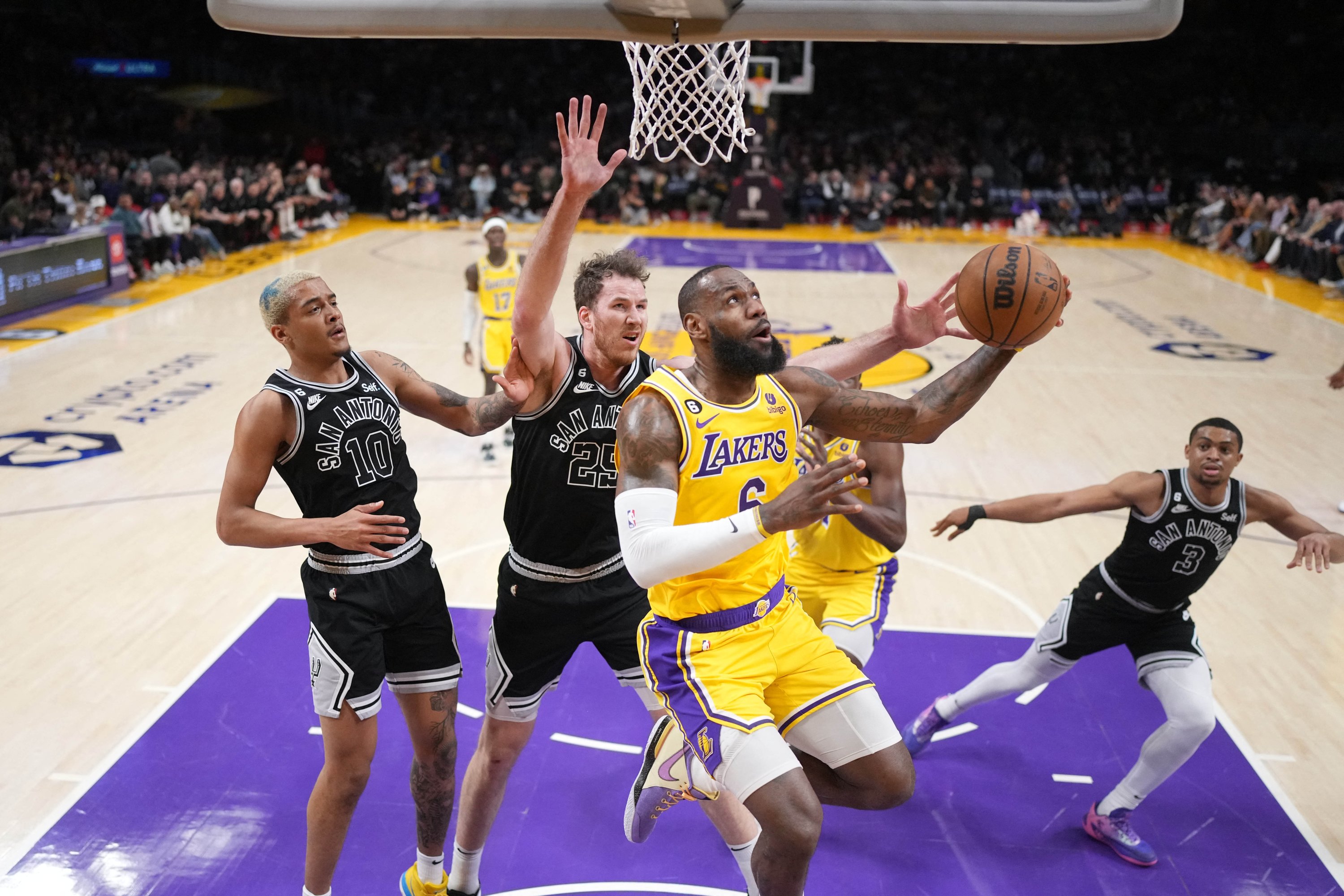 Penyerang Los Angeles Lakers LeBron James menembak ke arah penyerang San Antonio Spurs Jeremy Sochan dan center Jakob Poeltl pada babak pertama di Crypto.com Arena, Los Angeles, AS, 25 Jan 2023. (Foto Reuters)
