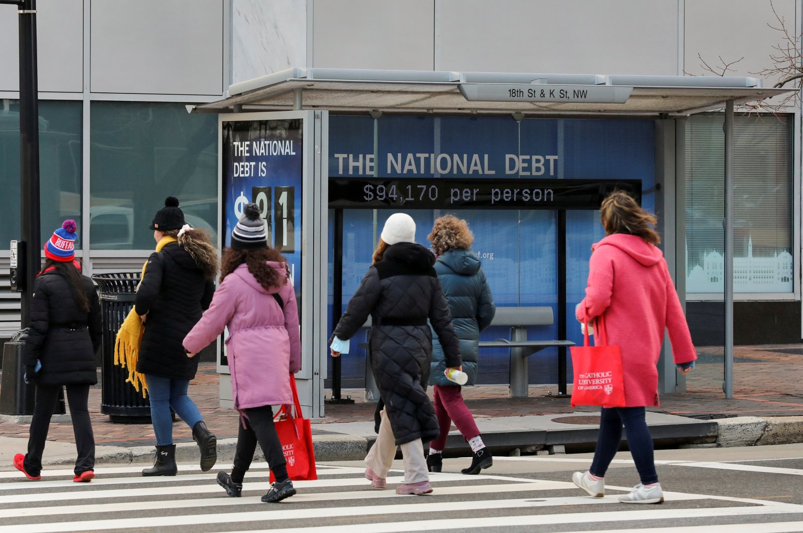 People cross the street next to a bus stop with a sign that shows a U.S. national debt figure in Washington, U.S., Jan. 20, 2023. (Reuters Photo)