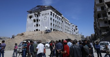 People gather in front of a hospital that locals referred as Point One (L), just meters away from where the alleged chemical weapons attack occurred, Douma, Syria, April 16, 2018. (AP Photo)