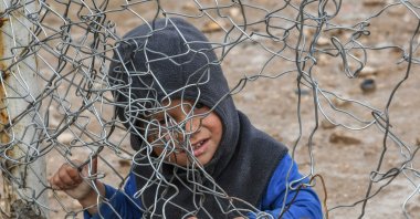 A child sits behind a wire fence in al-Hol camp run by the YPG/PKK terrorist organization, al-Hasakeh, Syria, March 28, 2019. (AFP Photo)