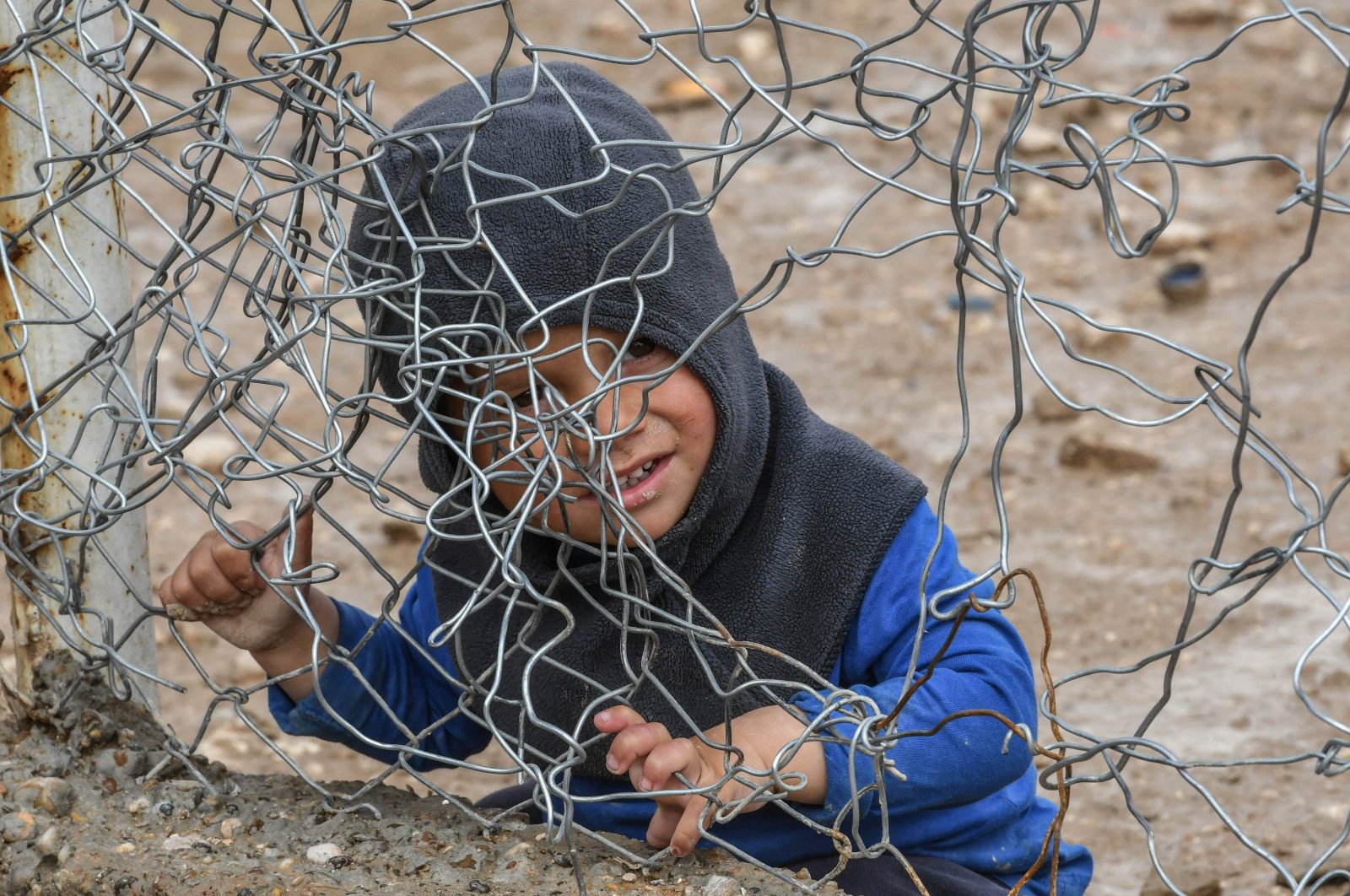 A child sits behind a wire fence in al-Hol camp run by the YPG/PKK terrorist organization, al-Hasakeh, Syria, March 28, 2019. (AFP Photo)