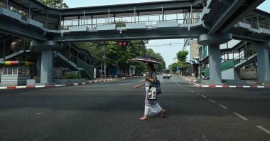 A woman crosses an almost empty street near Sule Pagoda during a "silent strike" to protest and mark the second anniversary of the coup, Yangon, Myanmar, Feb. 1, 2023. (AFP Photo)