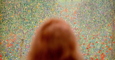 A woman looks at the painting &quot;Field of Poppies&quot; (1907) by Austrian painter Gustav Klimt, during a preview of an exhibition in Vienna, Austria, Feb. 2, 2023. (AFP Photo)