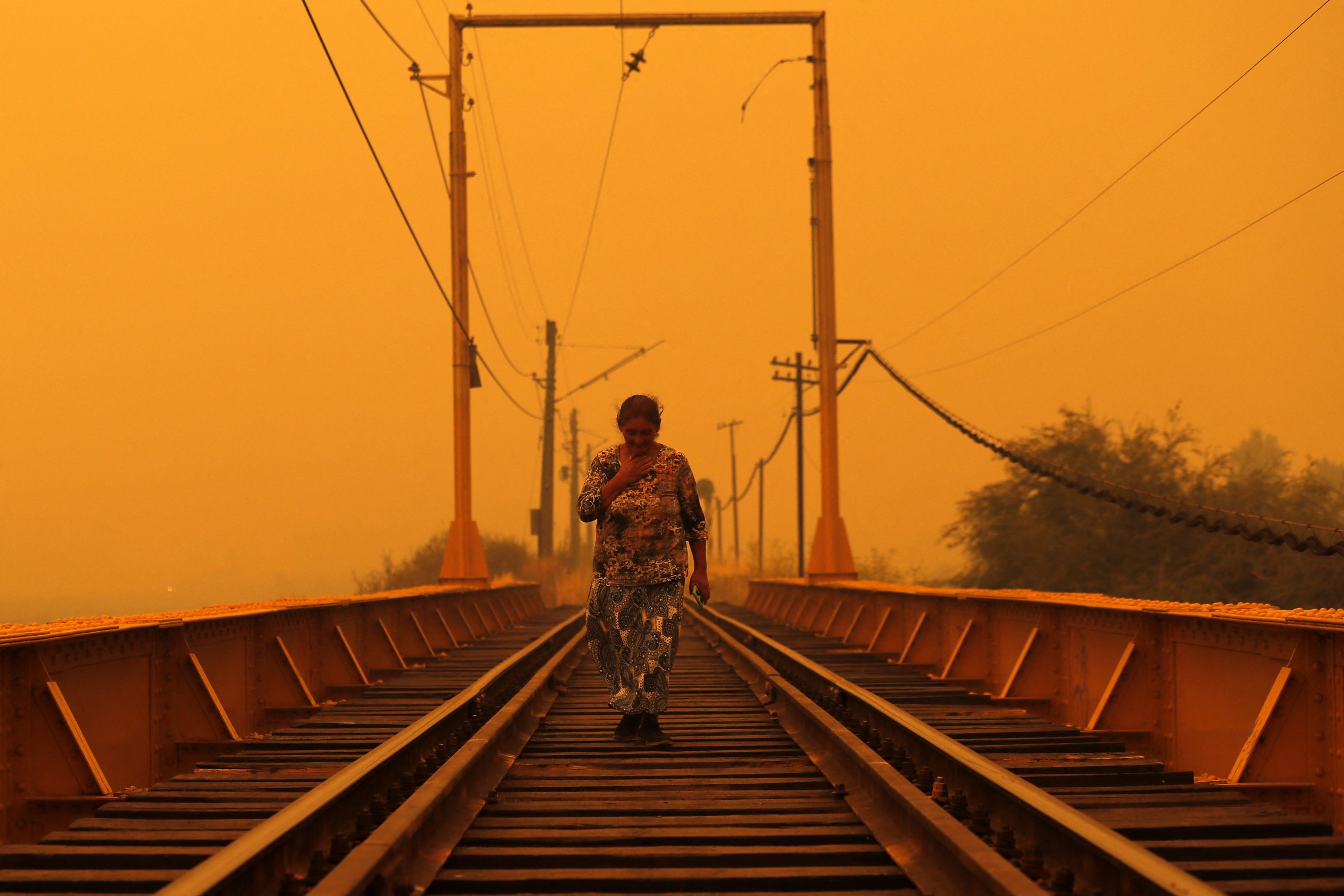 Seorang wanita berjalan di atas jembatan saat terjadi kebakaran di Renaico, wilayah Araucania, Chili, 4 Februari 2023. (Foto AFP)