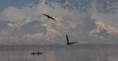 A boat ferries a passenger across the Dal lake with snow-covered mountains in the background during a winter day after fresh snowfall in Srinagar, Jammu and Kashmir, Jan. 31, 2023. (Getty Images Photo)