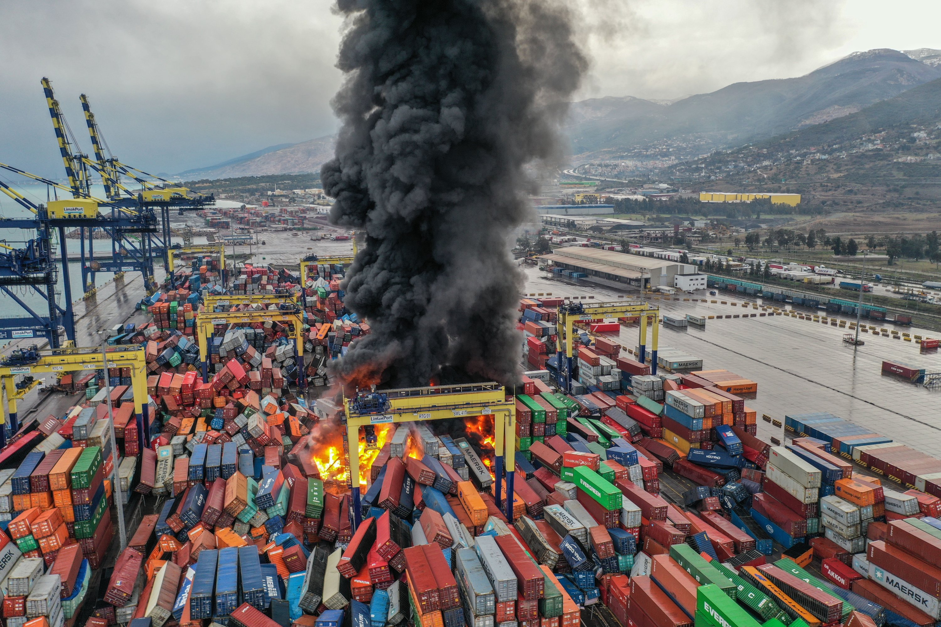 Asap gelap mengepul setelah kebakaran terjadi di antara kontainer yang terguling di pelabuhan utama di kota pesisir Mediterania Iskenderun setelah gempa bumi, Türkiye selatan, 6 Januari 2023. (Foto AA)