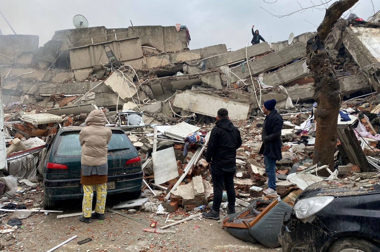 People stand in front of a collapsed building after an earthquake in Kahramanmaraş, Türkiye Feb. 6, 2023. (Reuters Photo)