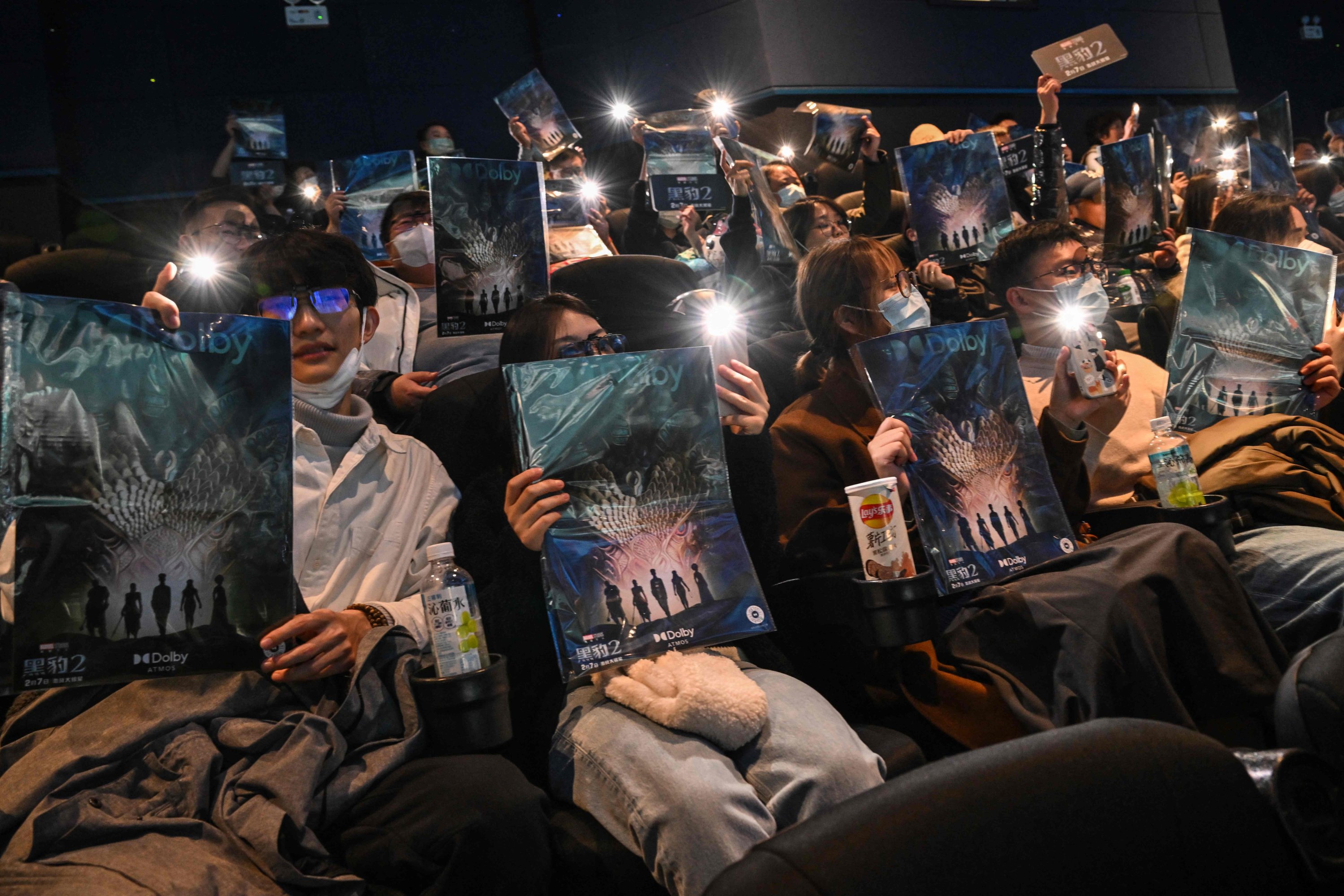 Anggota masyarakat memegang poster saat mereka menunggu untuk menonton film 