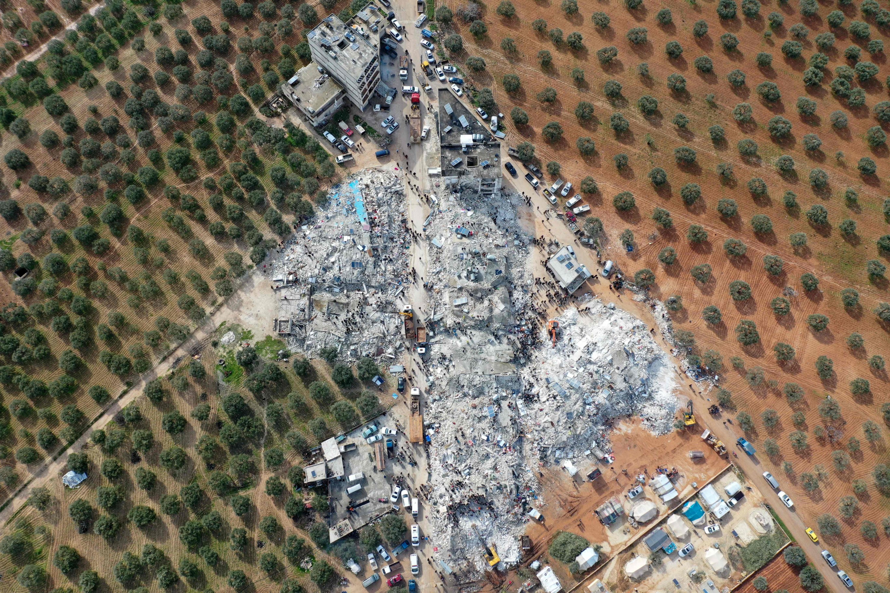 Pemandangan udara ini menunjukkan warga mencari korban dan penyintas di tengah puing-puing bangunan yang runtuh setelah gempa bumi di desa Besnia, Idlib, Suriah barat laut, 6 Februari 2022. (Foto AFP)