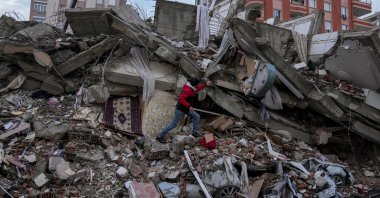 A man walks among rubble as he searches for people in a destroyed building in Adana, Türkiye, Feb. 6, 2023. (AP Photo)