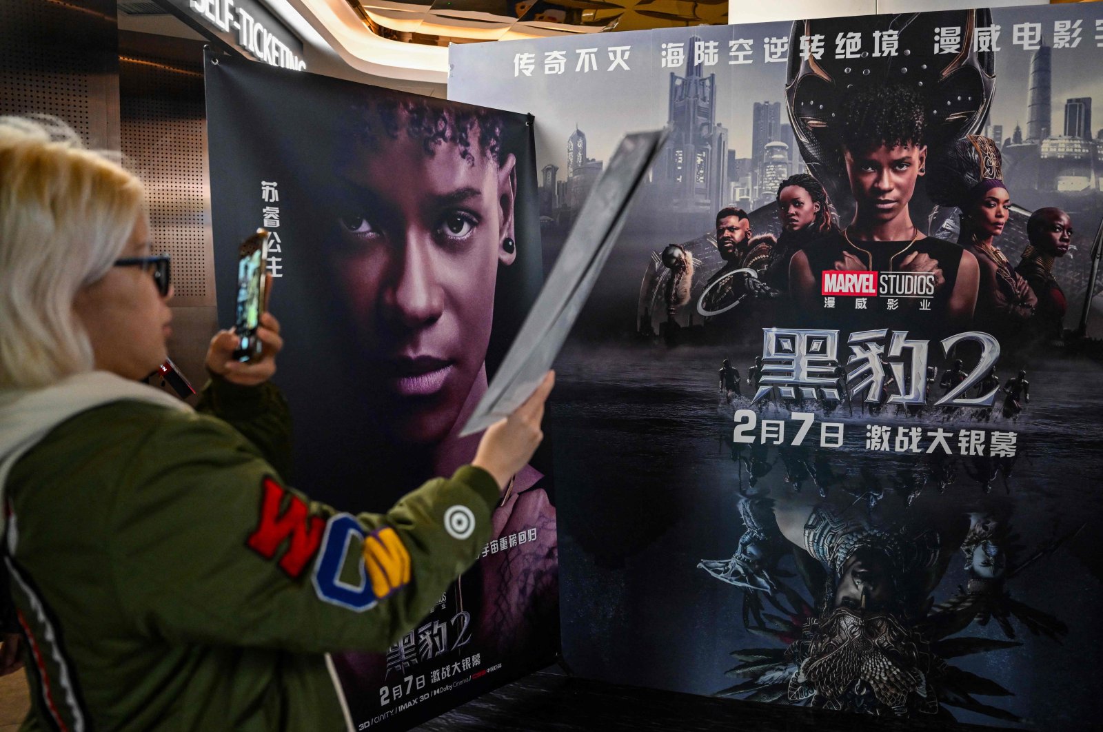 A young woman takes a picture of a poster before watching the movie &quot;Black Panther: Wakanda Forever&quot; at a cinema in Shanghai, China, Feb. 6, 2023. (AFP Photo)
