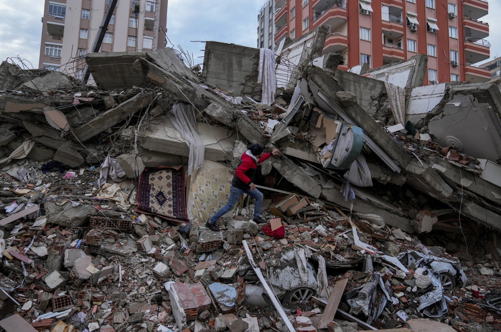 A man walks among rubble as he searches for people in a destroyed building in Adana, Türkiye, Feb. 6, 2023. (AP Photo)