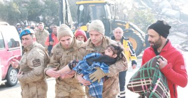 Soldiers of Turkish Armed Forces carries a child rescued from the debris of quake zone, Feb. 8, 2023. (DHA Photo)
