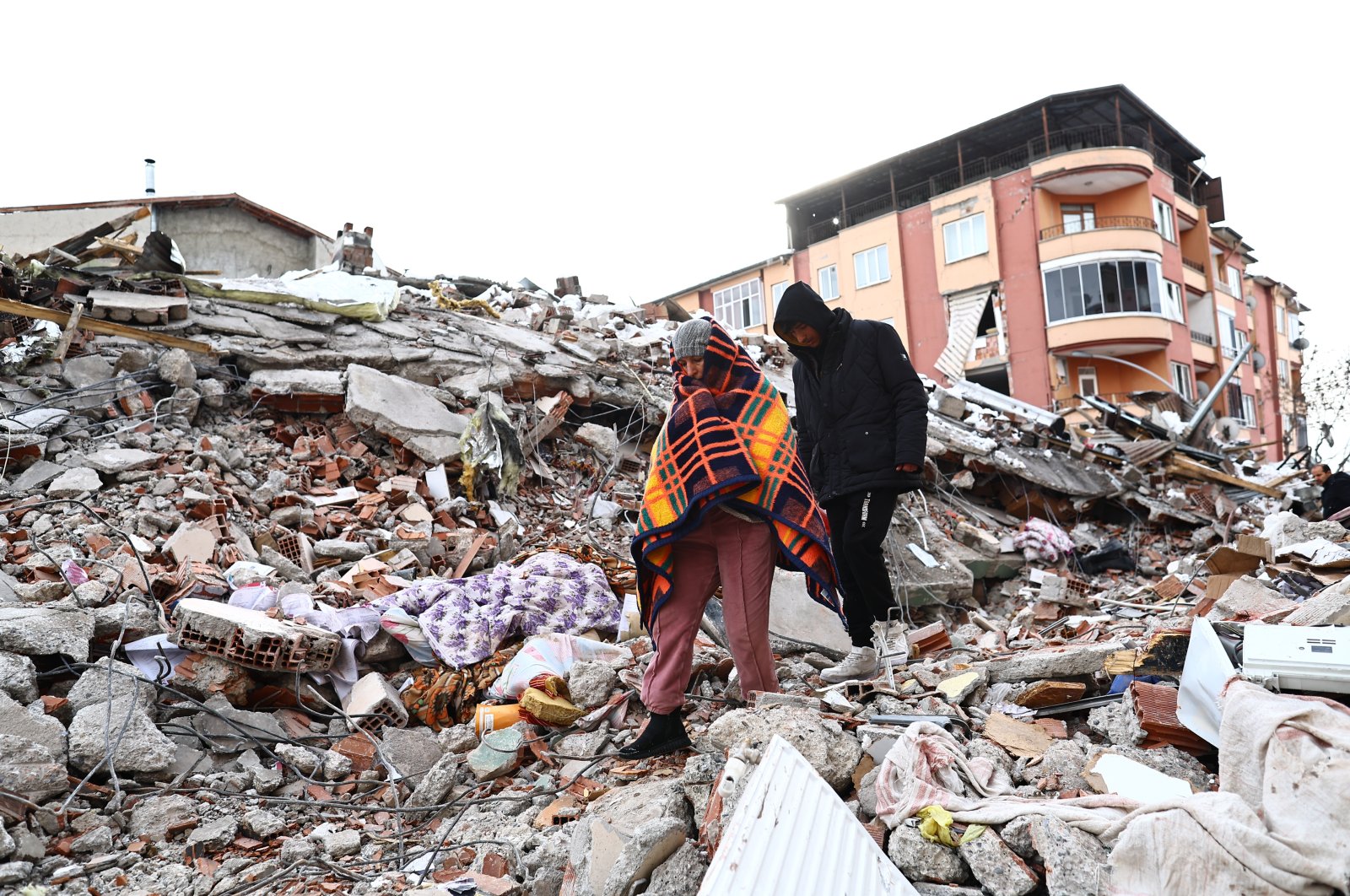 People walk over the rubble of a collapsed building in the aftermath of a major earthquake in the Elbistan district of Kahramanmaraş, Türkiye, Feb. 8, 2023. (EPA Photo)