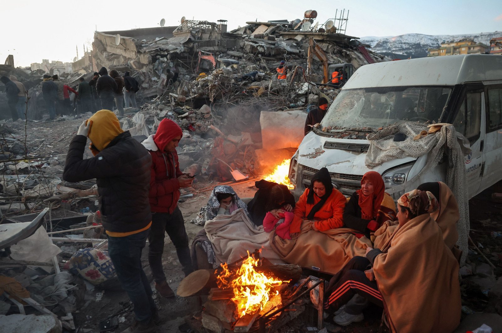Survivors gather next to a bonfire outside collapsed buildings in Kahramanmaraş, Feb. 8, 2023. (AFP Photo)