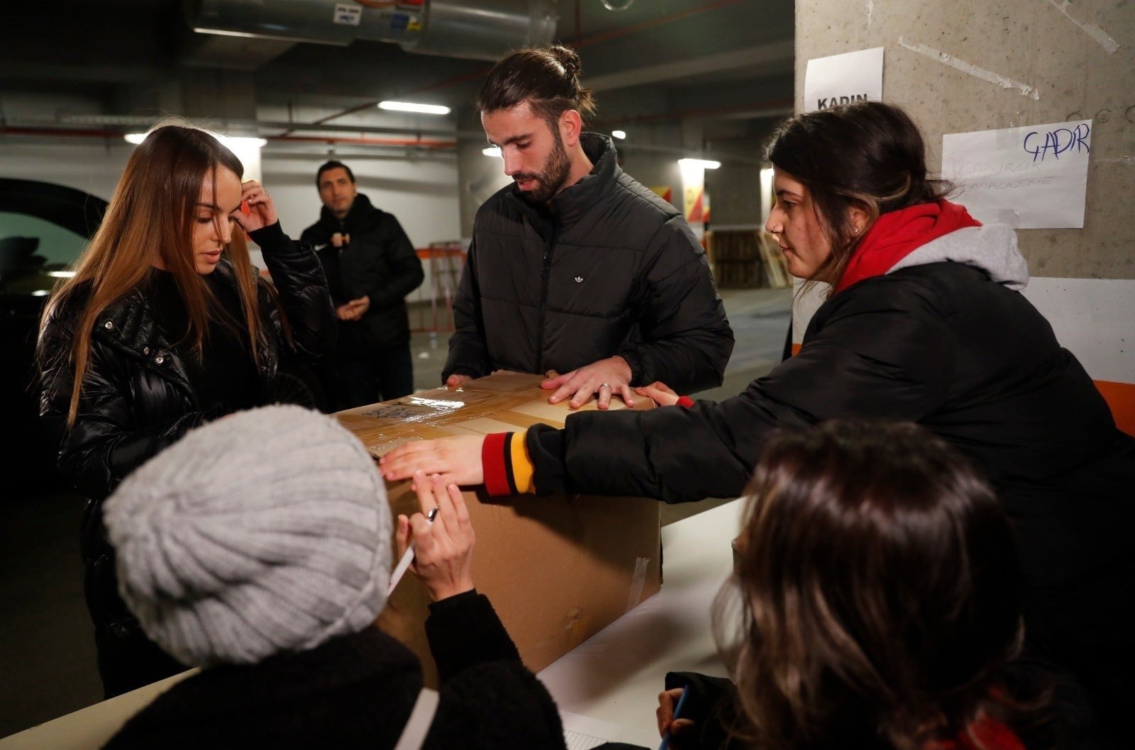 Sergio Oliveira dari Galatasaray (tengah) dan istrinya membantu relawan penyebab gempa Kahramanmaraş di Stadion Nef, Istanbul, 9 Februari 2023. (Foto IHA)