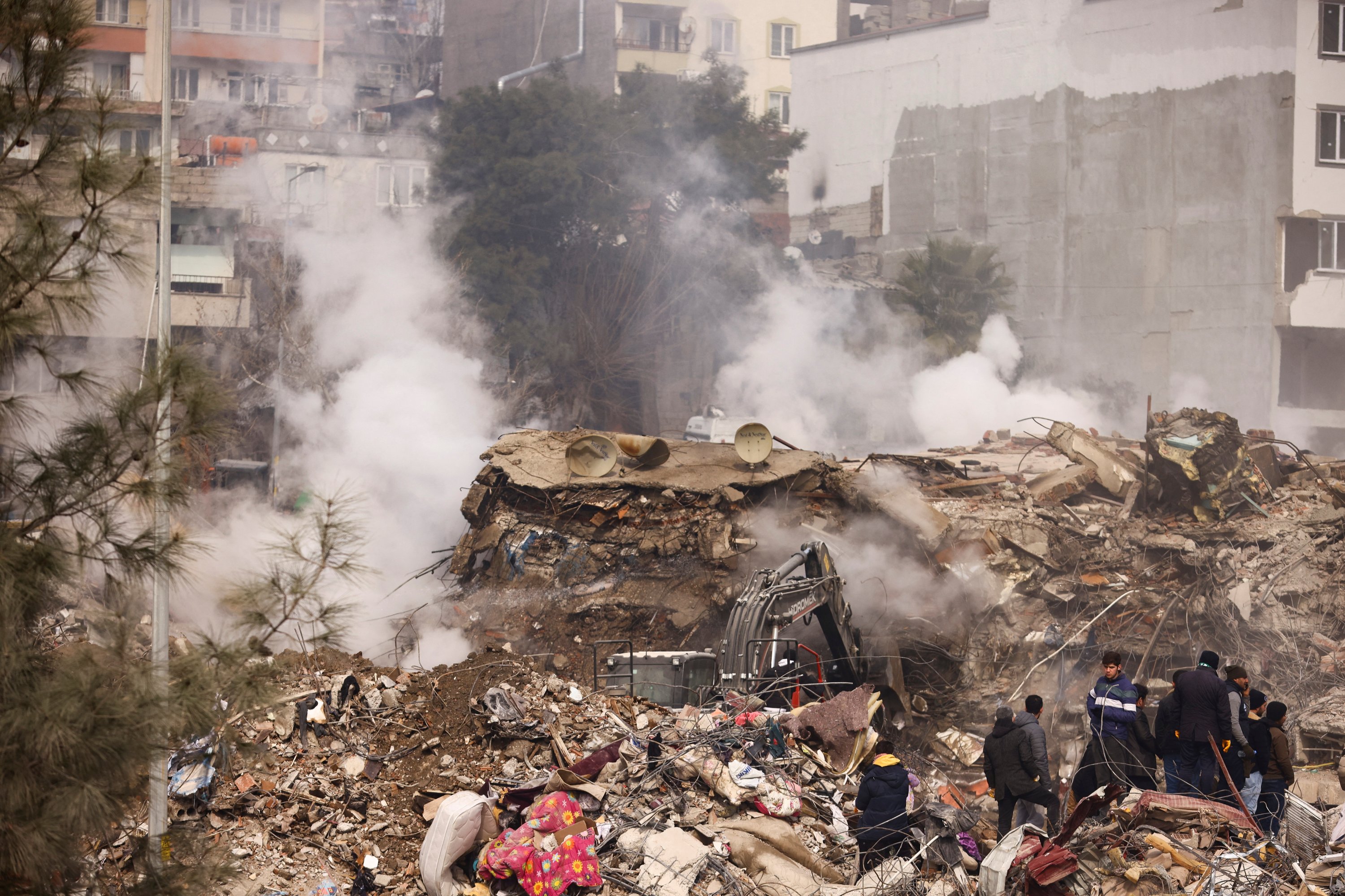 Orang-orang berdiri di tengah puing-puing setelah gempa mematikan, Kahramanmaras, Türkiye, 10 Februari 2023. (Foto Reuters)